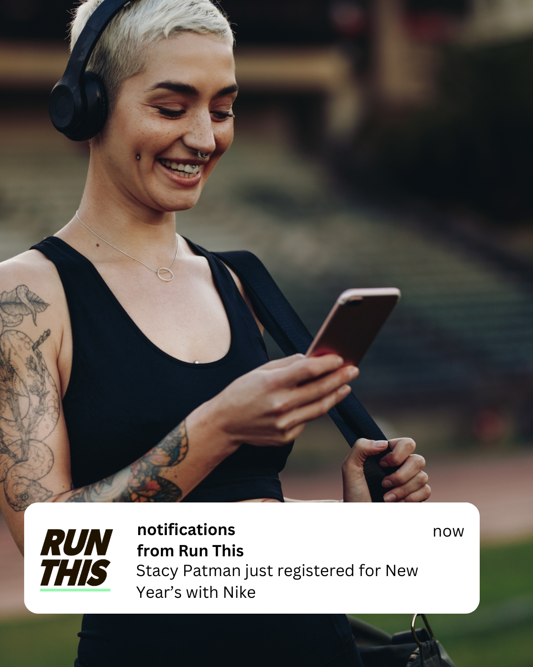 A runner smiling at her phone as a Run This notification tells her someone she follows just registered for a race